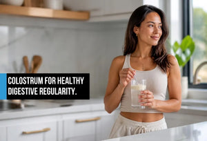 Woman in modern kitchen holding cold glass of colostrum powder drink supporting healthy digestive regularity