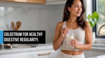 Woman in modern kitchen holding cold glass of colostrum powder drink supporting healthy digestive regularity
