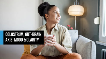 Woman sitting cross-legged on a sofa holding a mug and smiling contentedly, with text overlay reading Colostrum Gut-Brain Axis Mood and Clarity