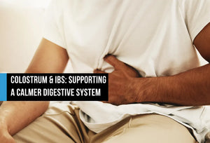 Person clutching their abdomen in discomfort while seated, with text overlay reading Colostrum and IBS Supporting a Calmer Digestive System