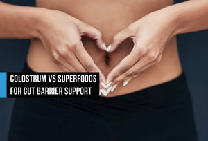 Woman forming a heart shape with her hands over her bare abdomen, with text overlay reading Colostrum vs Superfoods for Gut Barrier Support