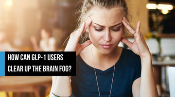 A woman pressing her fingers to her temples with her eyes closed in a cafe, looking mentally foggy, with overlay text reading 'How can GLP-1 users clear up the brain fog?'