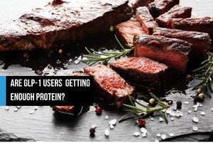 Cooked steak on a slate board with rosemary and peppercorns.