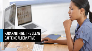 Woman working focused at a dual-monitor desk, concentrating on her screen — representing clean cognitive energy and mental clarity from paraxanthine.